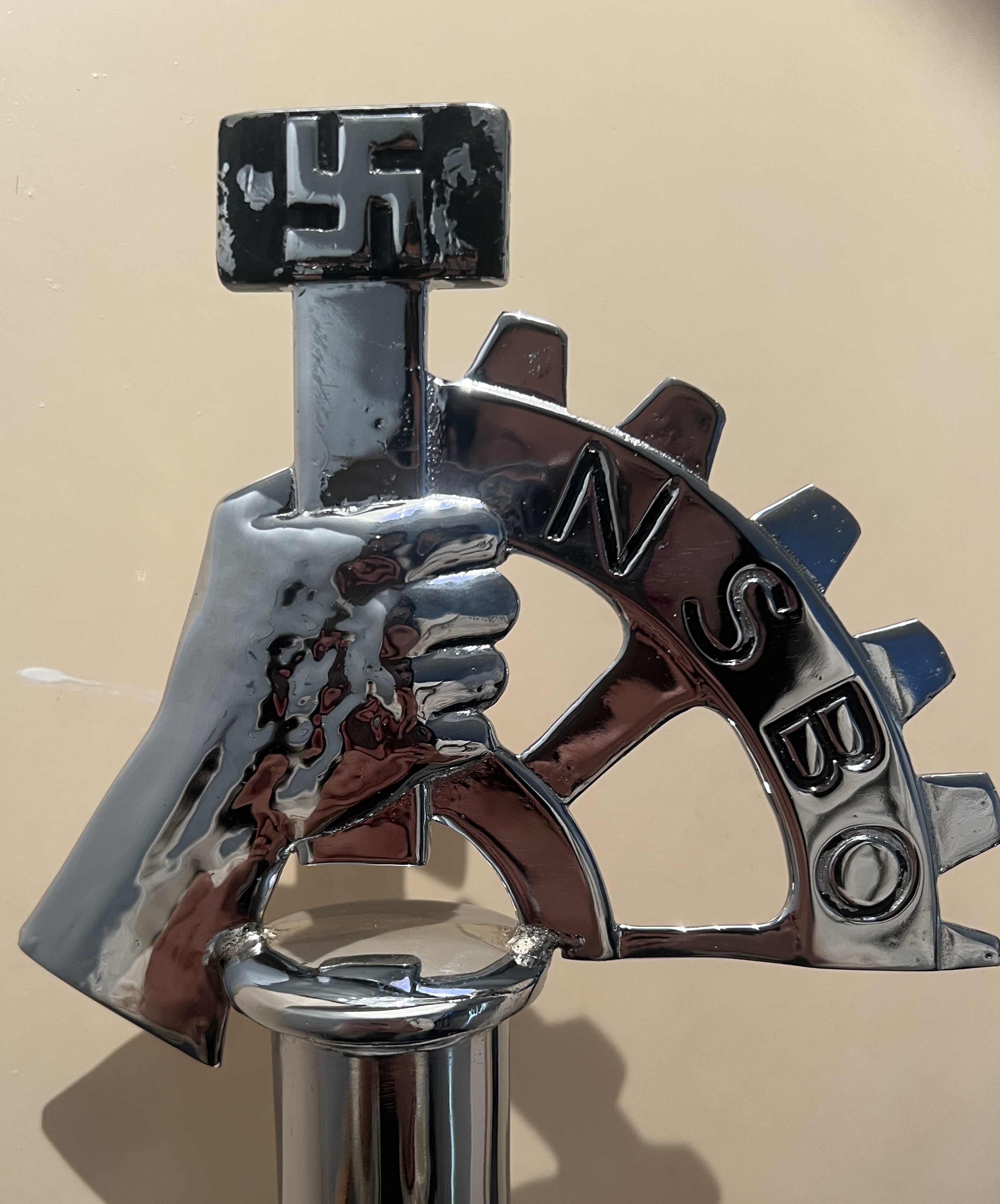 bright metal, hand holding hammer and swastika, quarter of cog and NSBO, obvious worker related item